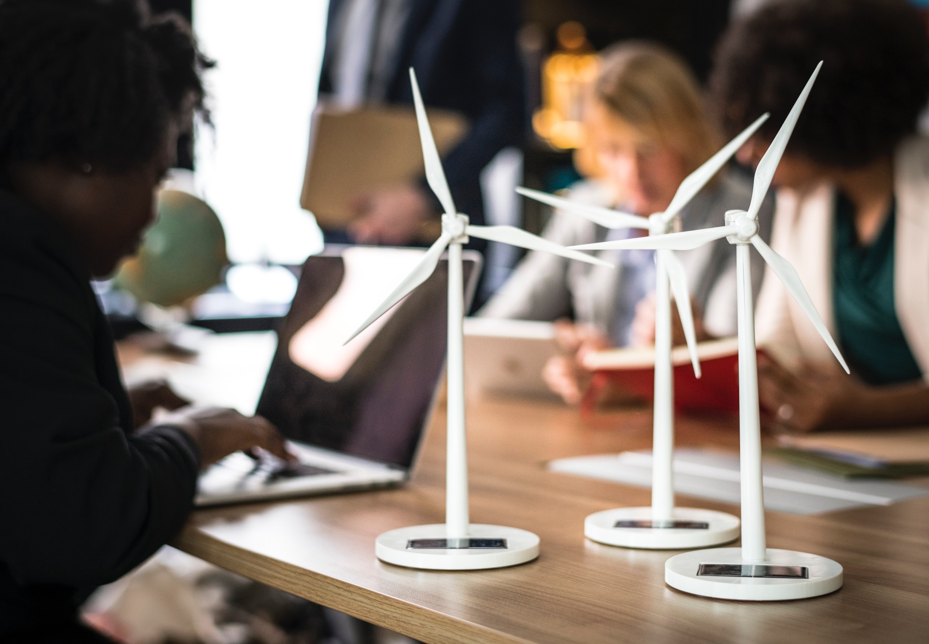 A few people work around a table with small replicas of energy producing windmills on the table.